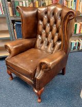 BROWN LEATHER BUTTONED WINGBACK ARMCHAIR ON QUEEN ANNE SUPPORTS.