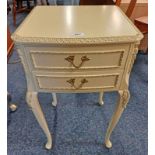 WHITE & GILT 2 DRAWER BEDSIDE TABLE ON SHAPED SUPPORTS.