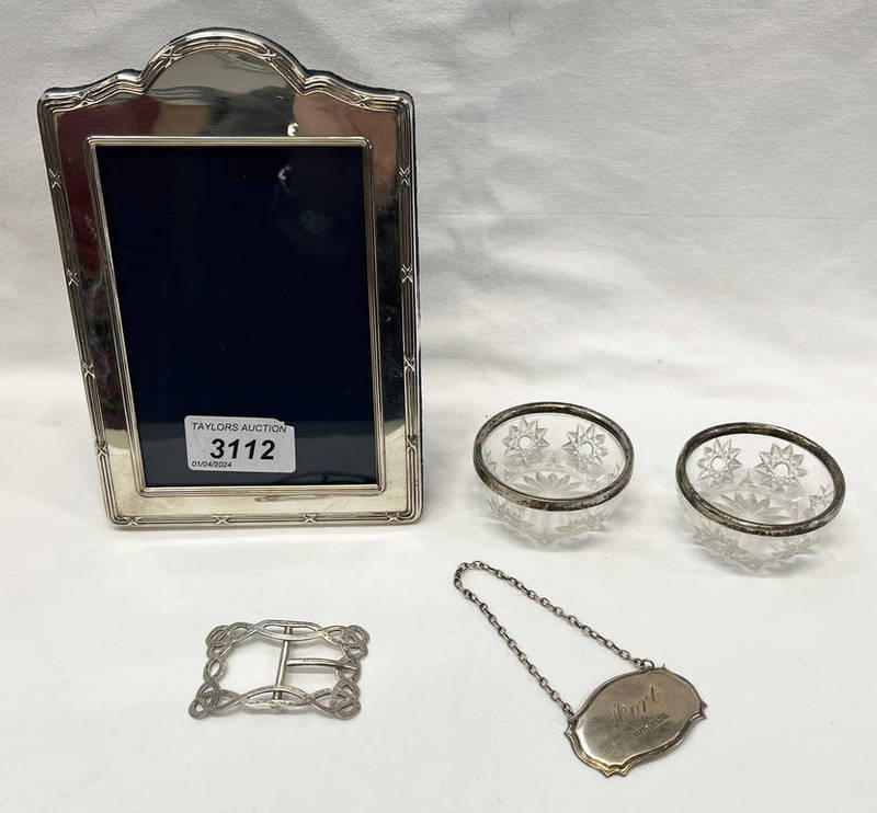 SILVER PORT LABEL, 2 SILVER RIMMED CUT GLASS SALTS, SILVER BUCKLE, SILVER RECTANGULAR FRAME.