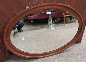 20TH CENTURY INLAID MAHOGANY FRAMED OVAL MIRROR WITH BEVELLED EDGE.