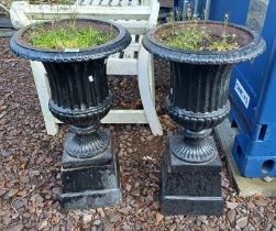 PAIR OF PAINTED CAST IRON GARDEN URNS ON SQUARE PLINTHS,