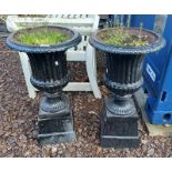 PAIR OF PAINTED CAST IRON GARDEN URNS ON SQUARE PLINTHS,