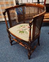 EARLY 20TH CENTURY BEECH FRAMED BERGERE TUB CHAIR WITH FLORAL TAPESTRY SEAT ON TURNED SUPPORTS.