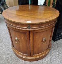 LATE 20TH CENTURY INLAID MAHOGANY CIRCULAR CABINET WITH 2 PANEL DOORS WITH BRASS LION MASK HANDLES.