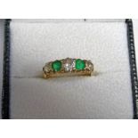 GOLD EMERALD & DIAMOND 5-STONE RING. THE THREE DIAMONDS APPROX. 0.