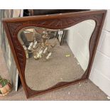 OAK FRAMED MIRROR WITH CARVED DECORATION & SHAPED BEVELLED GLASS.