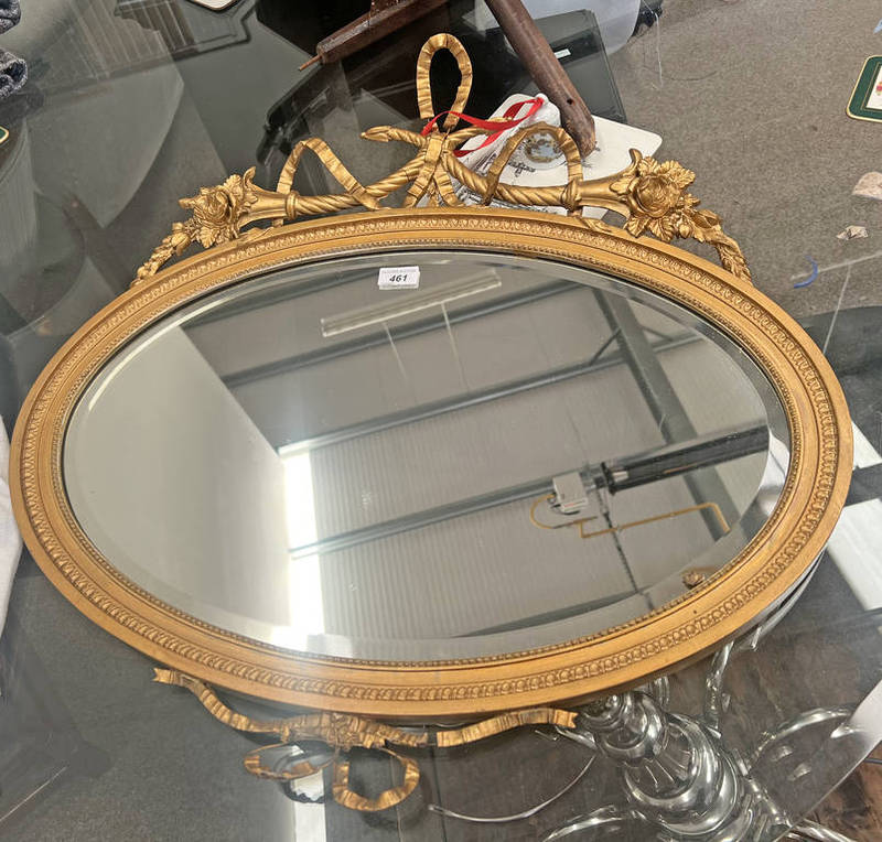 DECORATIVE GILT FRAMED OVAL MIRROR SURMOUNTED BY DECORATIVE BOW WITH FLORAL DECORATION.