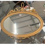 DECORATIVE GILT FRAMED OVAL MIRROR SURMOUNTED BY DECORATIVE BOW WITH FLORAL DECORATION.