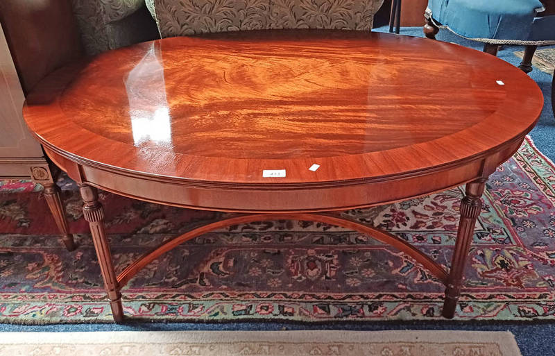 CROSSBANDED MAHOGANY OVAL COFFEE TABLE ON REEDED SUPPORTS WITH X - UNDERSTRETCHER.
