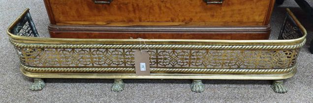 BRASS FIRE FENDER WITH PIERCED DECORATION ON BRASS PAW FEET,