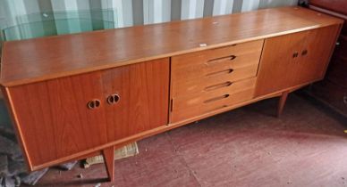TEAK SIDEBOARD WITH 5 CENTRALLY SET DRAWERS FLANKED ON EACH SIDE BY 2 PANEL DOORS ON TAPERED