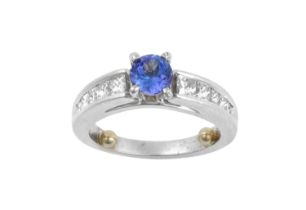 A Tanzanite and Diamond Ring the round cut tanzanite in a white claw setting, to graduated