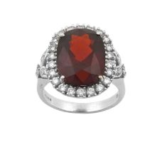 An 18 Carat White Gold Garnet and Diamond Cluster Ring the oval cut garnet within a border of