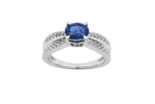 A Sapphire and Diamond Ring the oval cut sapphire in a white claw setting, to double row shoulders