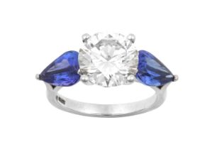 A Platinum Diamond and Tanzanite Three Stone Ring the round brilliant cut diamond flanked by pear