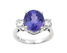 An 18 Carat Gold Tanzanite and Diamond Three Stone Ring the oval cut tanzanite flanked by round