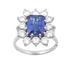 A Platinum Tanzanite and Diamond Cluster Ring the emerald-cut tanzanite within a border of round