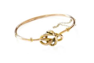 A Lover's Knot Motif Hinged Bangle, with applied plaque stamped '9CT', inner measurements 6.2cm by