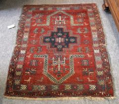 An Unusual Karabagh Rug, the madder field with indigo stepped medallion flanked by two niches