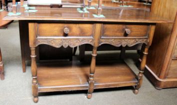 A Waring & Gillow Ltd Oak Two Drawer Side Table, with scroll carved apron, turned supports and under