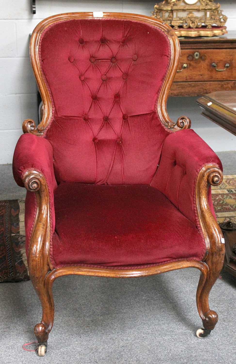 A Victorian Oak-Framed Armchair, circa 1870, recovered in buttoned red velvet, with a moulded and