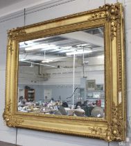 A Victorian Gilt and Gesso Framed Mirror, gadrooned, with scrollwork spandrels and mercury plate,