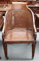 An Early 19th Century Bergere Armchair, with down scrolled arms and tapering reeded legs, moving