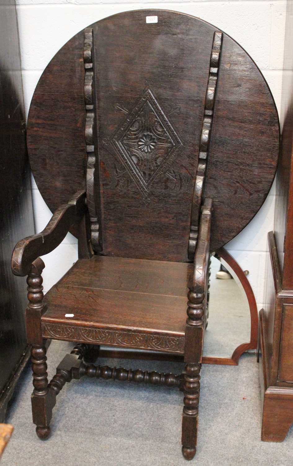 A 1920's Carved Oak Monks Chair, with tilt table top on turned supports