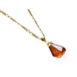 An Amber Pendant on Chain, the irregular shaped amber pendant on a 9 carat gold figaro link chain,