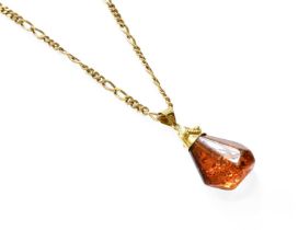 An Amber Pendant on Chain, the irregular shaped amber pendant on a 9 carat gold figaro link chain,