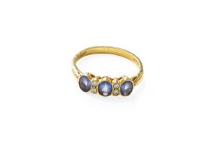 An 18 Carat Gold Tanzanite and Diamond Ring, three oval cut tanzanites spaced by pairs of round