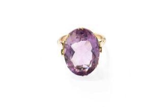 An Amethyst Ring, the oval cut amethyst in a yellow double claw setting, to a tapered shoulder plain