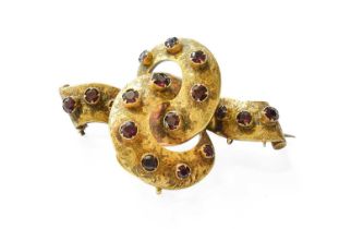 A Garnet Brooch/Pendant, the yellow engraved ribbon motif set throughout with round cut garnets,