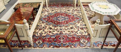 Mashad Carpet, the ivory ground centred by a magenta medallion enclosed by floral borders, signed,