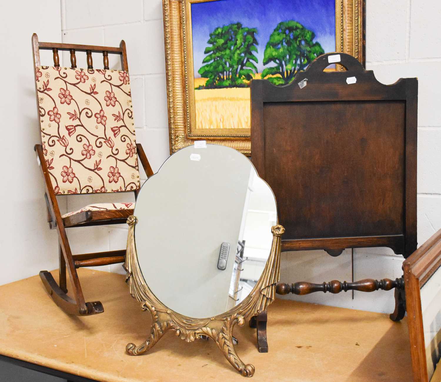 A Folding Oak and Part-Upholstered Rocking Chair, circa 1920, A Shaped Strut Mirror, with gilt