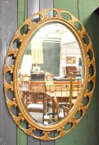 An Oval Gilt Framed Hanging Mirror, with bevelled plate and open C scroll border, 104cm by 74cm