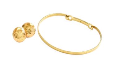 A 9 Carat Gold Diamond Bangle, the round brilliant cut diamond in a yellow rubbed over setting, to a