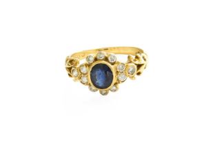 An 18 Carat Gold Sapphire and Diamond Cluster Ring, the oval cut sapphire within a border of round