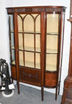 An Edwardian Mahogany Display Cabinet, with carved and reeded frieze, bowed sides and tapering