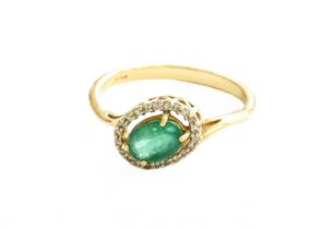A 9 Carat Gold Emerald and Diamond Cluster Ring, the oval cut emerald in a yellow claw setting,