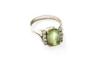 A 14 Carat White Gold Peridot and Diamond Ring, the oval cut peridot flanked by a row of four