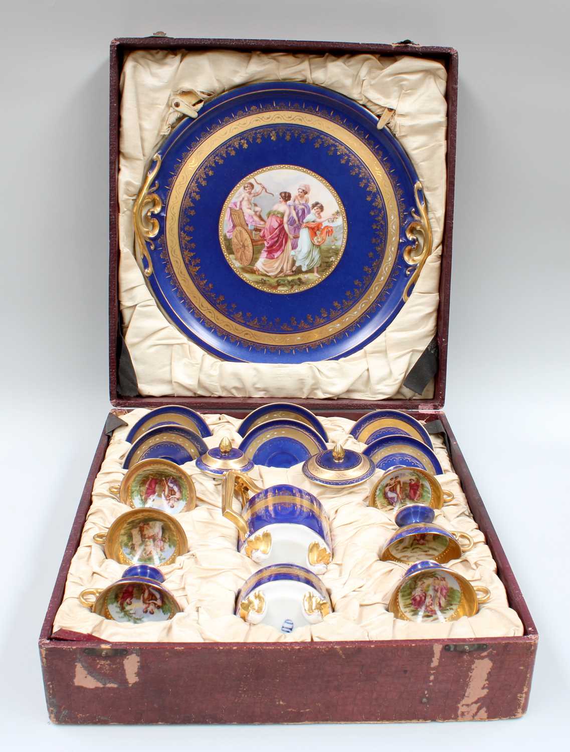 A Vienna Style Porcelain Coffee Set, in fitted case, ground in blue, gilded and printed with