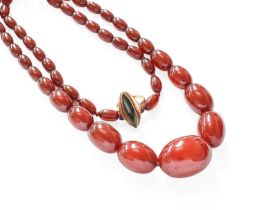 A Graduated Amber Bead Necklace, length 71cm; and A Nephrite Ring, the marquise shaped nephrite in a