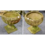 A Pair of Stone Neo-Classical Garden Urns, with relief foliate friezes, on socle plinth bases,
