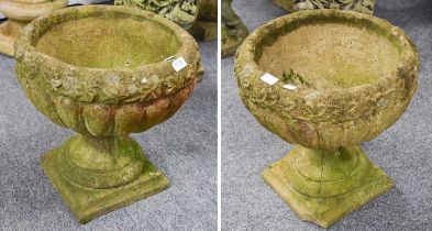 A Pair of Stone Neo-Classical Garden Urns, with relief foliate friezes, on socle plinth bases,