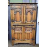 A Titchmarsh & Goodwin Style Oak Cupboard, two carved doors over brushing side, two further doors