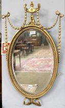 An Early 20th century Adam Revival Gilt and Gesso Wall Mirror, of oval form with elaborate urn