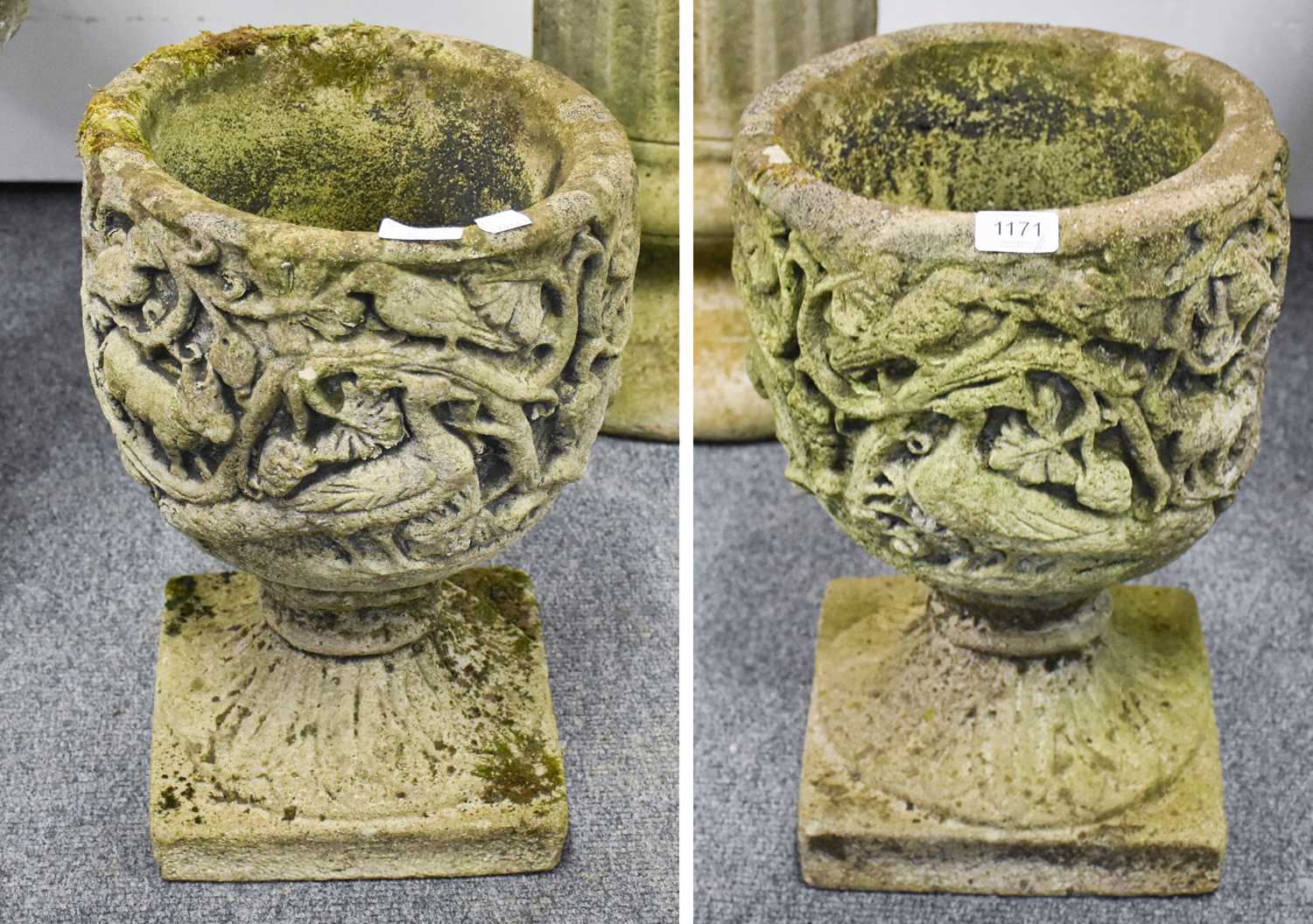 A Pair of Composite Garden Urns, decorated in relief with various creatures and birds within
