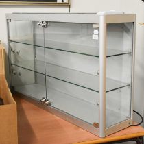 A Glazed Wall Mounted Shop Cabinet, 98cm by 60cm by 25cm Locked and without keys.