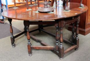 An 18th Century and Later Walnut and Oak Gateleg Table, oval top with twin drop leaves, raised on